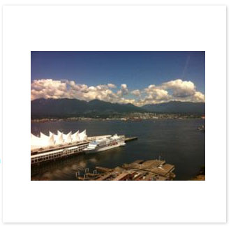 Canada Place and the Vancouver harbour with the North Shore mountains behind, photographed through a window
